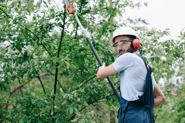 Serious Gardener Helmet Trimming Trees Telescopic Pole Saw Looking Camera — Stock Photo, Image