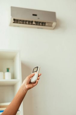 partial view of african american woman using air conditioner remote controller clipart