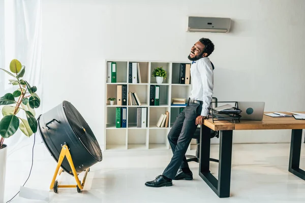 Εξαντλημένος Αφρικανός Αμερικανός Επιχειρηματίας Στέκεται Μπροστά Από Τον Ηλεκτρικό Αναπνευστήρα — Φωτογραφία Αρχείου