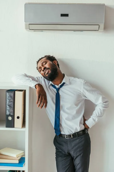 Uitgeput Afro Amerikaanse Zakenman Staande Onder Conditioner Vasthouden Hand Hip — Stockfoto