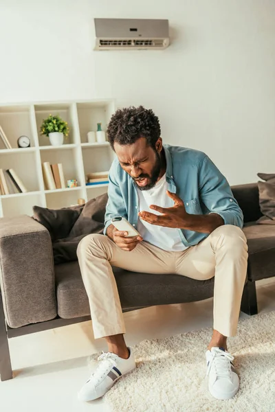 Hombre Afroamericano Irritado Sosteniendo Control Remoto Del Aire Acondicionado Mientras — Foto de Stock