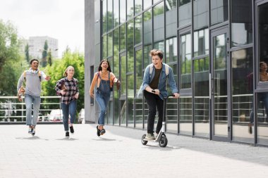 mutlu ve neşeli arkadaşlar gülümseyen, çalışan ve scooter sürme 