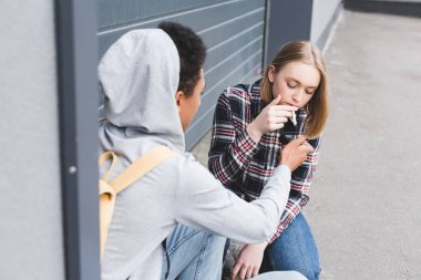 african american boy lighting cigarette of blonde and pretty teen clipart