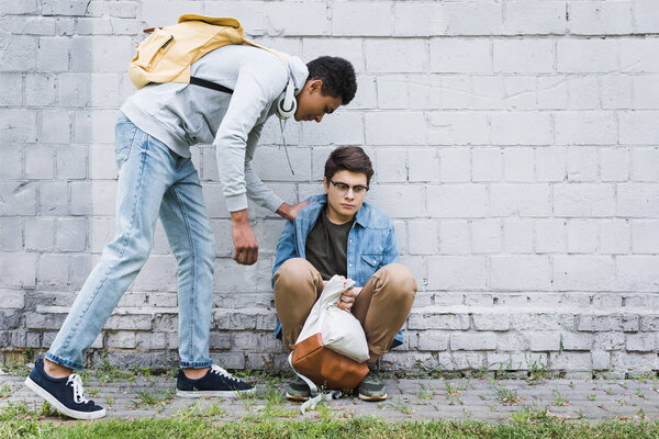 african american boy in hoodie and jeans bulling boy in glasses 