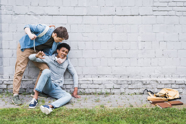 aggressive boy in shirt bulling, going to punch african american boy in hoodie 