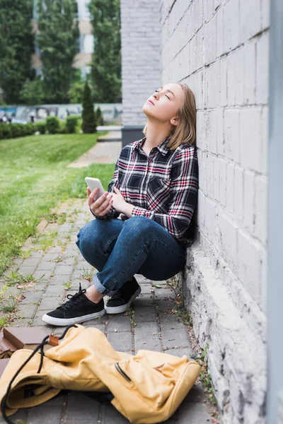 Déçu Blond Adolescent Chemise Jeans Assis Près Mur Tenant Smartphone — Photo