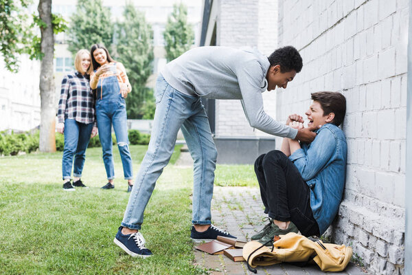 african american boy in hoodie and jeans bulling boy and teenager shooting it 