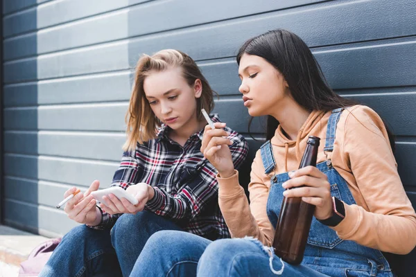 Bonitos Amigos Fumando Cigarrillos Sosteniendo Cerveza Sentado Mirando Teléfono Inteligente — Foto de Stock