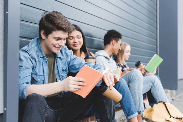 Adolescentes Felizes Sentados Falando Segurando Copos Papel Lendo Livro — Fotografia de Stock