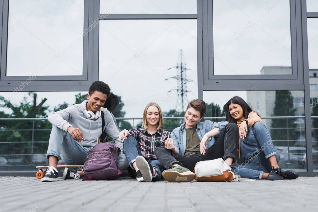 happy and positive friends smiling, sitting and smoking cigarettes