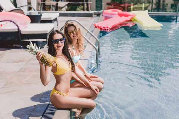 Happy Blonde Brunette Girls Sitting Swimming Pool Pineapple — Stock Photo, Image
