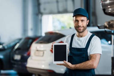 neşeli araba tamirciaraba servisinde boş ekran ile dijital tablet tutan 