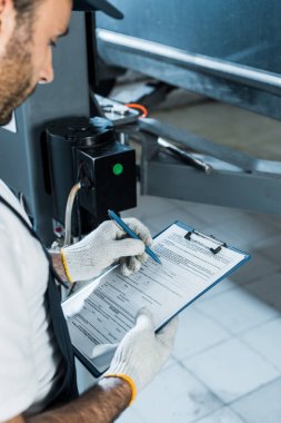 araba servisinde yazarken oto tamircisi tutma panosu kırpılmış görünümü 