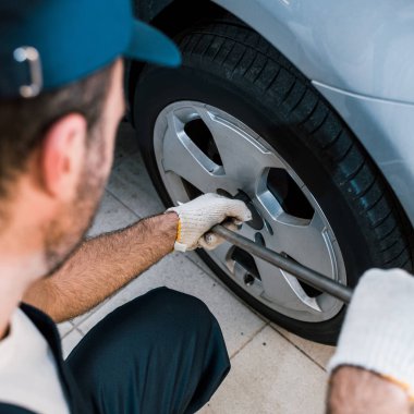 selective focus of car mechanic changing car tire in car service  clipart