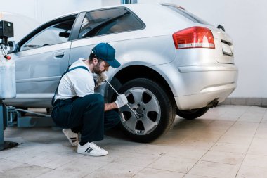 üniformalı sakallı araba tamircisi araba servisinde araba lastiği değiştirme 