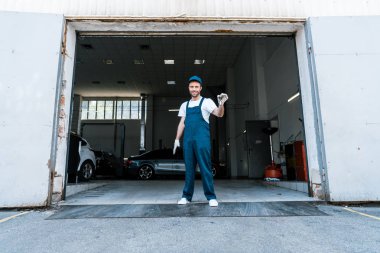 garaj yakınında anahtarları tutan mutlu sakallı araba tamircisi 