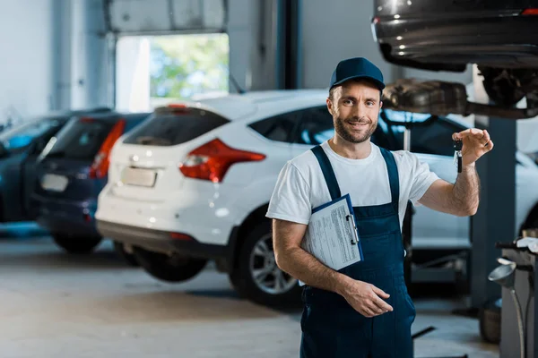 Mecánico Del Coche Barbudo Feliz Mirando Cámara Sujetando Portapapeles Llave — Foto de Stock