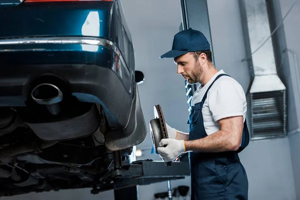 Selektivní Zaměření Pohledného Automechanika Přidržením Kovového Detailu Poblíž Automobilu — Stock fotografie