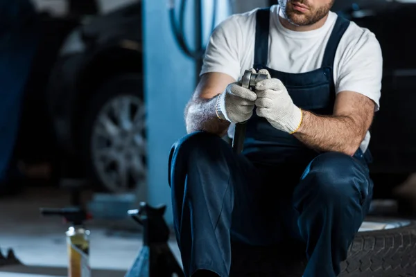 車のタイヤに座っている間 金属工具を保持する車の整備士のトリミングビュー — ストック写真