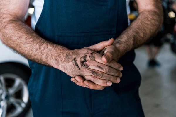 cropped view of car mechanic standing with mud on clenched hands 