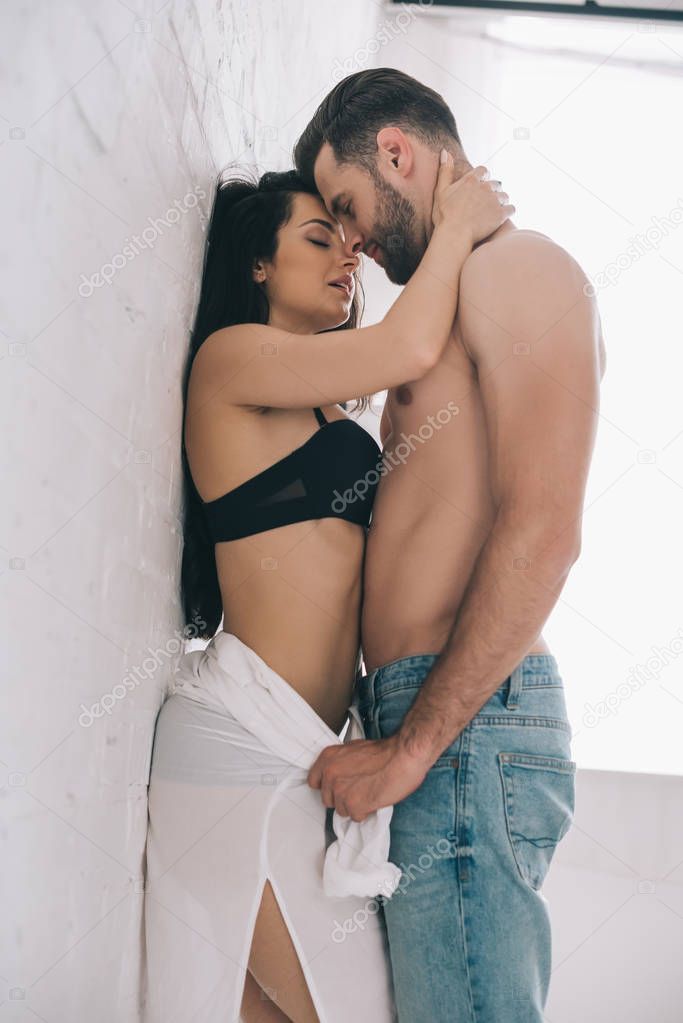 low angle view of sexy man hugging and kissing with brunette and passionate woman 