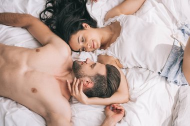 yatakta çekici kadın ile yalan yakışıklı ve gömleksiz adam üst görünümü 
