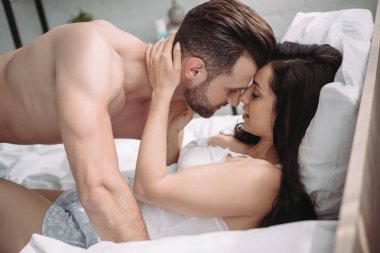 çekici kadın yatakta yatarken ve yakışıklı ve seksi adam ile öpüşme 