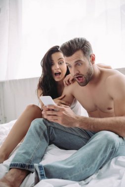 shocked beautiful woman and handsome man looking at smartphone 