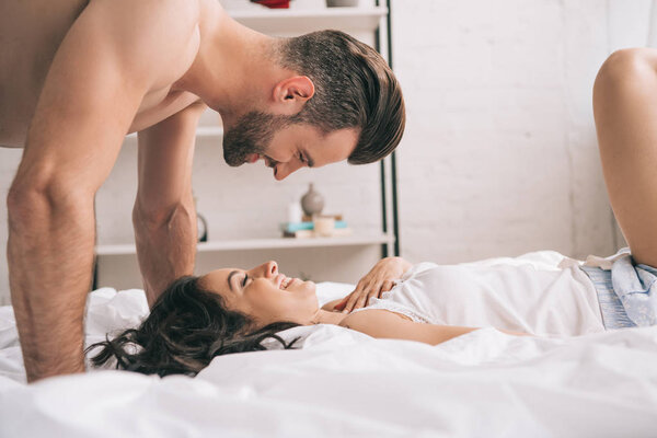 side view of handsome man looking at woman lying on bed 