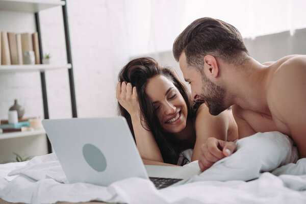 beautiful woman and handsome man lying on bed with laptop 