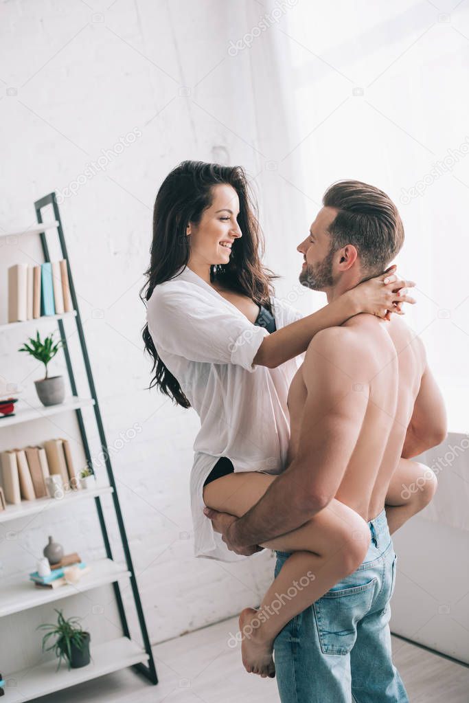 handsome man in jeans holding and hugging with sexy woman in shirt 