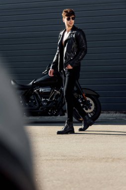 siyah motosiklet yakınında duran genç adamın seçici odak