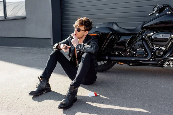 Joven Guapo Con Cigarrillo Gafas Sol Sentado Suelo Cerca Motocicleta — Foto de Stock