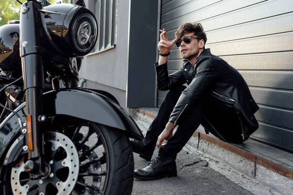 Schöner Motorradfahrer Mit Sonnenbrille Sitzt Auf Dem Boden Neben Motorrad — Stockfoto
