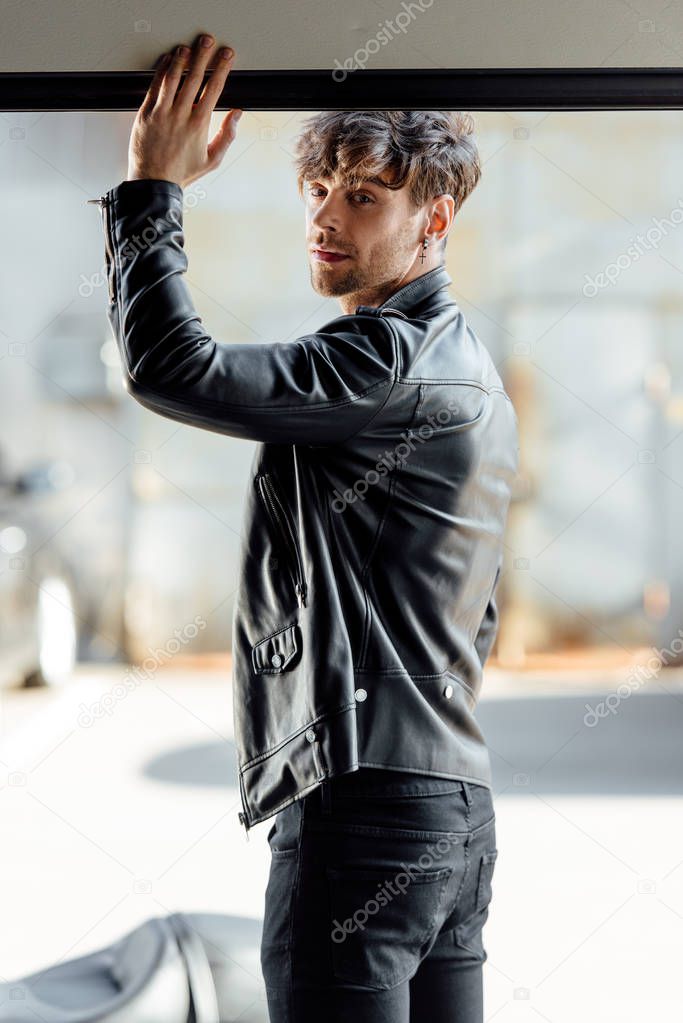 full length view of shirtless motorcyclist standing near motorcycle outside and looking away