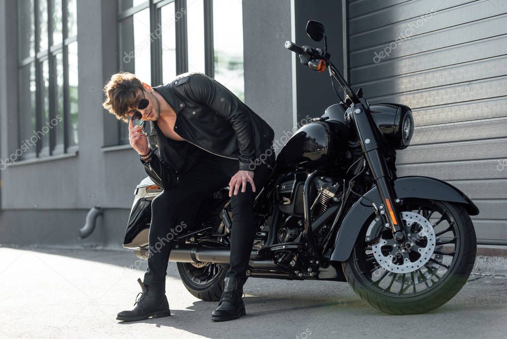 handsome man sitting on black motorcycle and looking on camera