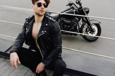 motosiklet ve metal tüpler üzerine yaslanmış genç adam seçici odak