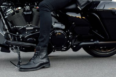 motosiklet üzerinde oturan siyah çizmeli adamın kırpılmış görünümü