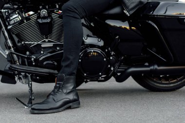 cropped view of man in black boot sitting on motorcycle clipart