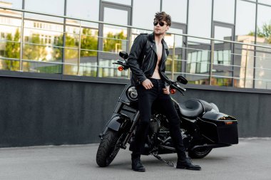 full length view of shirtless motorcyclist standing near motorcycle outside  clipart
