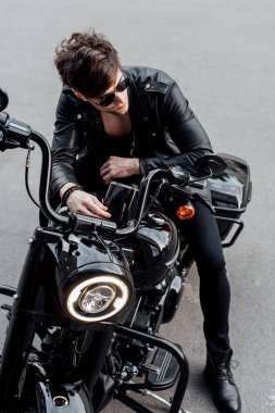 high angle view of young man in leather jacket sitting on motorcycle clipart