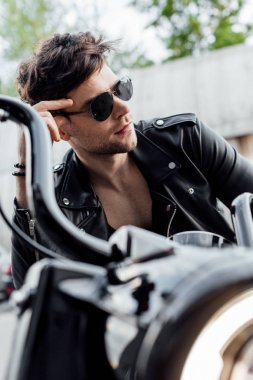 güneş gözlüğü yakışıklı adam seçici odak motosiklet üzerinde oturan ve uzağa bakarak