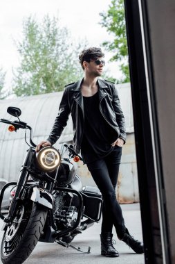 motosiklet yanında duran ve ona yaslanmış deri ceket yakışıklı adam tam uzunlukta görünümü 