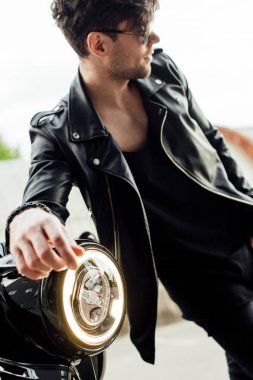 motocycle ışık lambası seçici odak ve motosiklet yakınında duran güneş gözlüğü yakışıklı adam