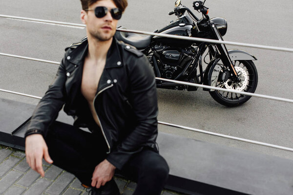 selective focus of motorcycle and young man leaning on metal tubes