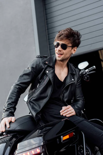 Handsome Motorcyclist Sunglasses Leather Jacket Smiling While Sitting Motorcycle Garage — Stock Photo, Image