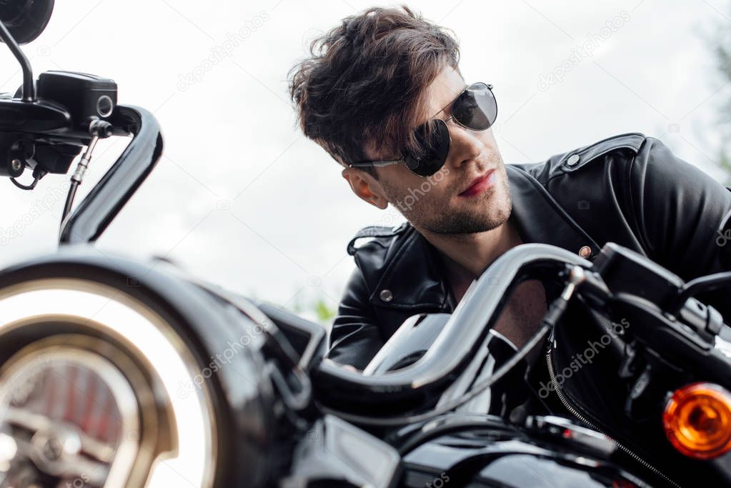 selective focus of lighting up lamp and handsome man sitting on motorcycle and looking away