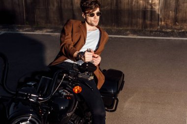 motosiklet üzerinde yatan ve alkol şişesi tutan kahverengi ceket yakışıklı genç adam 