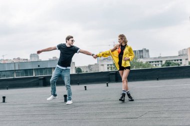 çekici kadın ve yakışıklı adam eller tutarak ve çatıda gülümsüyor 