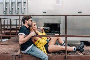 sarışın kadın içme şampanya ve adam çatıda oturan yan görünümü 